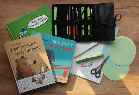 Foto einer Gruppe von Gegenständen auf einem Tisch: Kinderbücher und Schreibutensilien