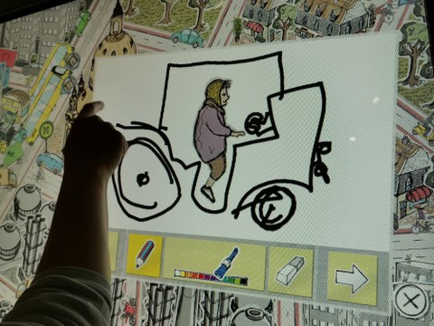 Foto: eine Kinderhand zeichnet auf einem Touchdisplay ein Auto