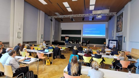 Foto eines Hörsaals mit Rückenansichten zahlreicher Zuhörer:innen