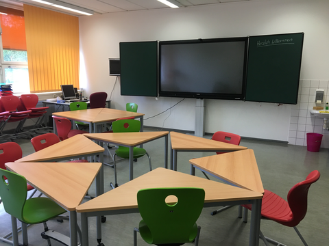 Foto eines Seminarraumes mit Tischen, Stühlen und einer digitalen Tafel