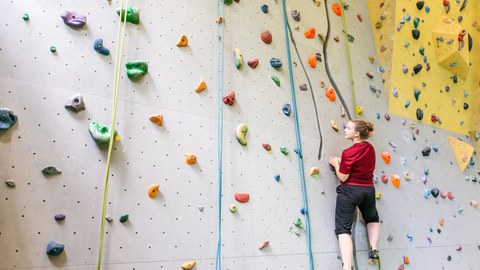 Foto einer Frau, die an einer Kletterwand klettert