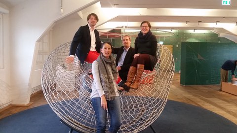 Bild einer Gruppe von 4 Personen, die vor bzw. auf einem Exponat im "Erlebnisland Mathematik" der Technischen Sammlungen Dresden posieren.