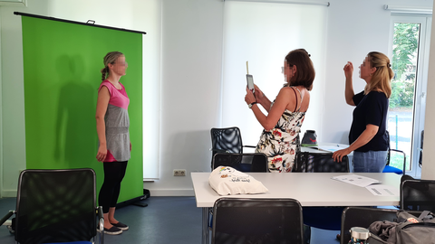 Zwei Frauen fotografieren eine dritte Frau, welche vor einem Green Screen steht.