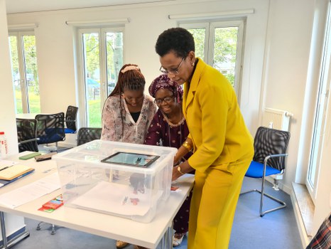 Drei Frauen arbeiten zusammen an einem Erklärvideo mithilfe einer Plastikbox und eines Tablets.