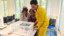 Drei Frauen arbeiten zusammen an einem Erklärvideo mithilfe einer Plastikbox und eines Tablets.