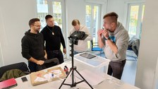 Vier Männer, die gerade einen Erklärfilm mithilfe der Legetechnik aufnehmen.