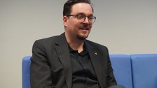 Mann sitzt auf Sofa und diskutiert dabei