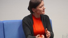Frau sitzt auf Sofa und diskutiert dabei