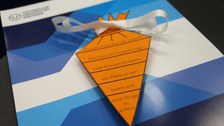 Abgebildet ist eine flache Papier-Schultüte mit schriftlichen guten Wünsche für die wissenschaftliche Ausbildung.