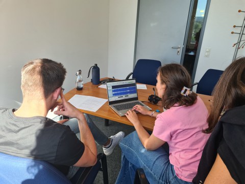 Zwei personen arbeiten an einem laptop, von hinten fotografiert