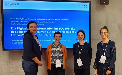 Gruppenbild von 4 Frauen vor einem großen Bildschirm
