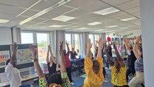 Gruppe von Personen, die in einer Lernwerkstatt zusammen Yoga ausüben.