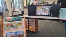 Mini Theater Aufbau auf einem Tisch und Kinderbücher in einem Regal.