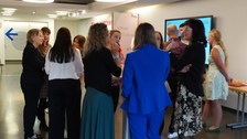 Gruppe von ca. 10 Frauen stehen in Kleingrüppchen in einem Foyer und unterhalten sich