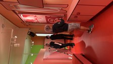 Rot ausgeleuchteter Ausstellungsraum, wo 3 Personen zu sehen sind