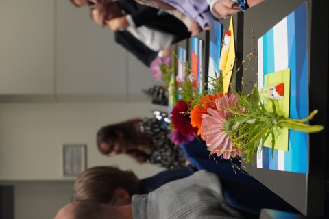 Strauß Blumen und Zeugnismappen liegen auf Tischen im Hörsaal