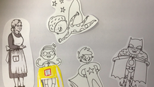 Es ist ein Bild, das mit Papierfiguren mittles Legetechnik gelegt wurde. Man sieht ein Schulkind, drei Superhelden-Kinder und eine Lehrerin bzw. ein Dienstmädchen.