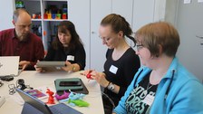 vier Personen arbeiten an einem Tisch zusammen 