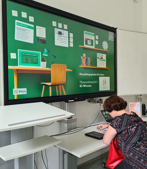 Eine junge Frau sitzt vor einer digitalen Tafel