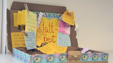 Im Mittelpunkt des Bildes steht eine bunte, aufgeklappt Lernkiste, auf der viele gelbe Postits mit Fragen und Notizen angebracht wurden.