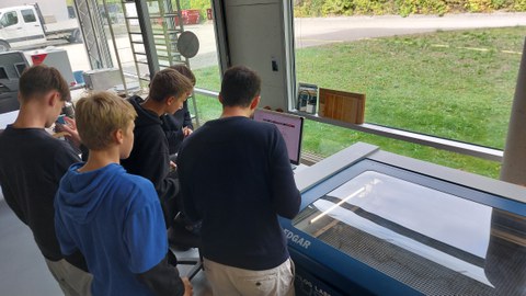 SuS die neben einem Lasercutter stehen und an einem PC eine Visitenkarte gestalten