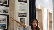 Das Foto zeigt eine Frau, die etwas in einem Museum erklärt. 